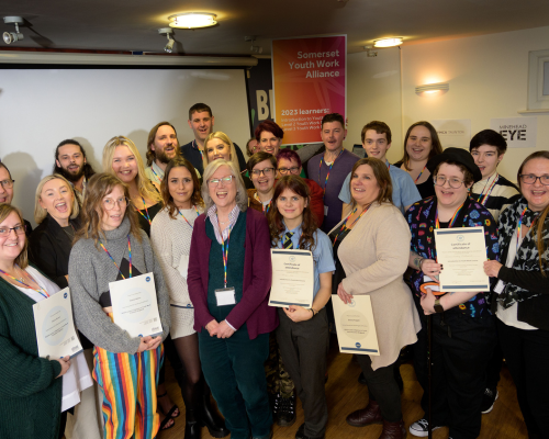 Photograph of a group of youth workers holding their qualification certificates, smiling