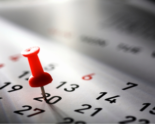 Close up photograph of a calendar with a pin in it.