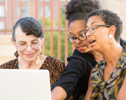 A diverse group of women sat at a laptop, engaging with what's on the screen